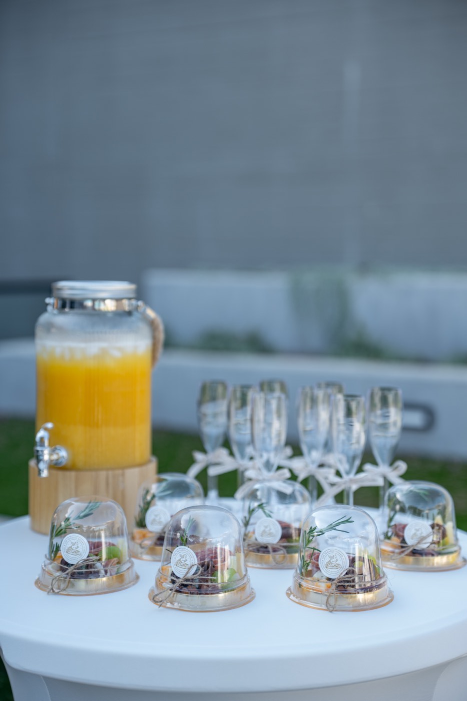 Mesita coctelera con domos individuales de charcutería y agua fresca de naranja